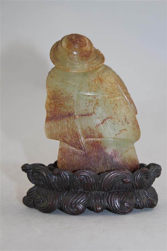 A Chinese celadon and russet skin jade figure of a fisherman, 18th / 19th century, 10cm., loss to right foot, carved wood stand